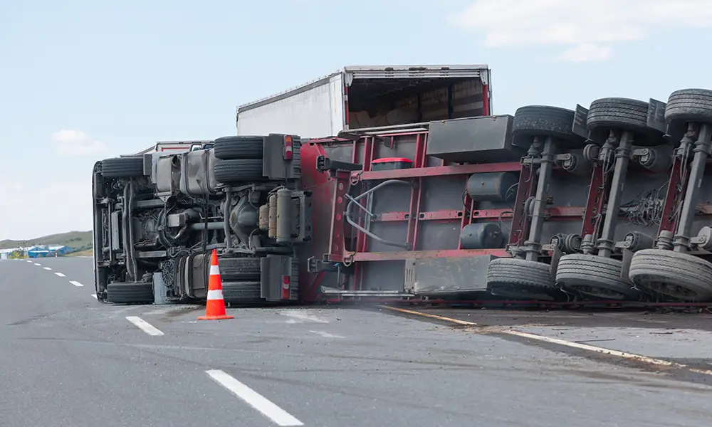 overturned semi-truck on the side of the highway