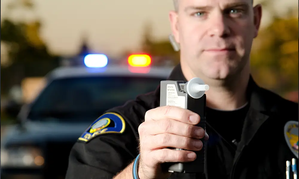 cop standing with a breathalyzer - Collinsville IL DUI/DWI defense lawyer may be needed