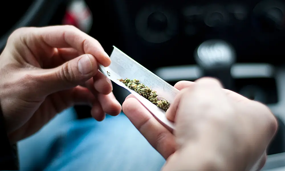 person rolling up marijuana to smoke in car - drug dui defense lawyer Collinsville IL