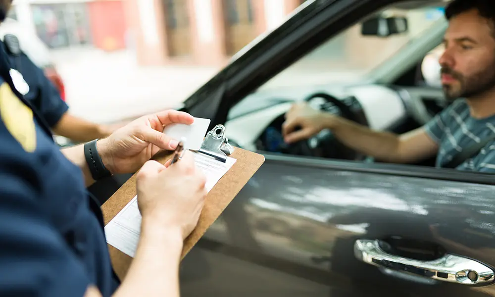 police officer writing a traffic ticket to a male driver - traffic ticket defense collinsville il