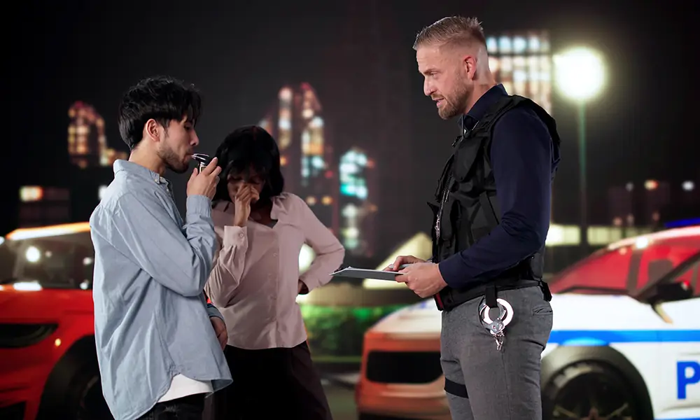 Driver Taking Breathalyzer Test As Passenger Watches With Concern